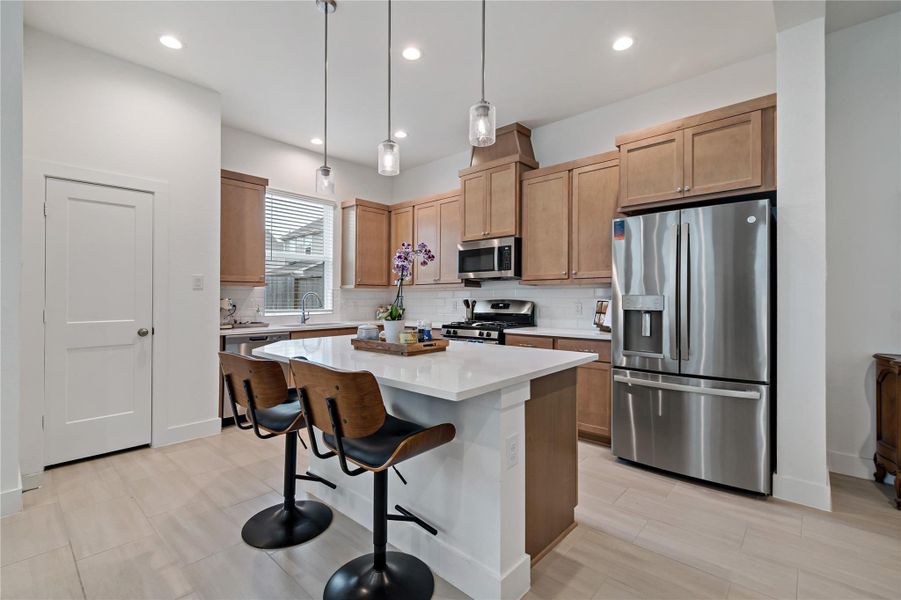 Modern kitchen featuring sleek stainless steel appliances, elegant wood cabinetry, and a spacious island with seating, perfect for entertaining. Modern kitchen featuring sleek stainless steel appliances, elegant wood cabinetry, and a spacious island with seating, perfect for entertaining.