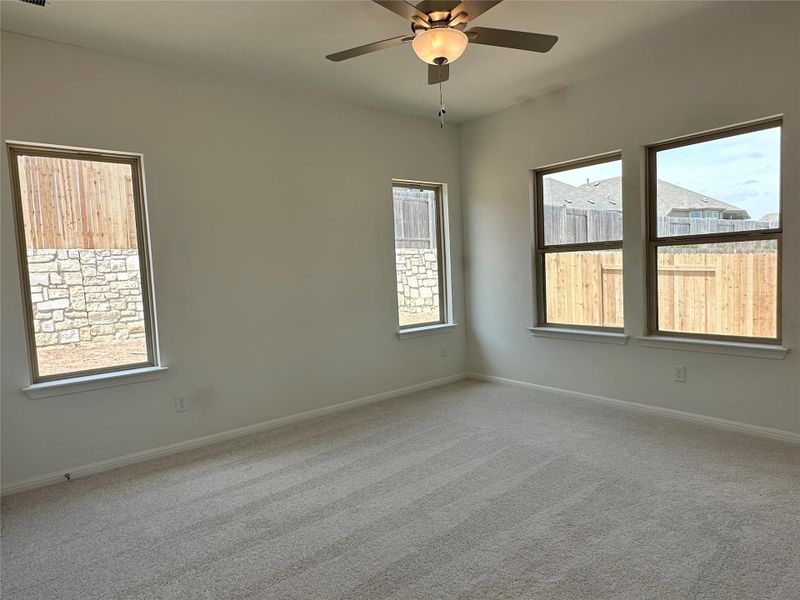 Carpeted empty room with baseboards and a ceiling fan