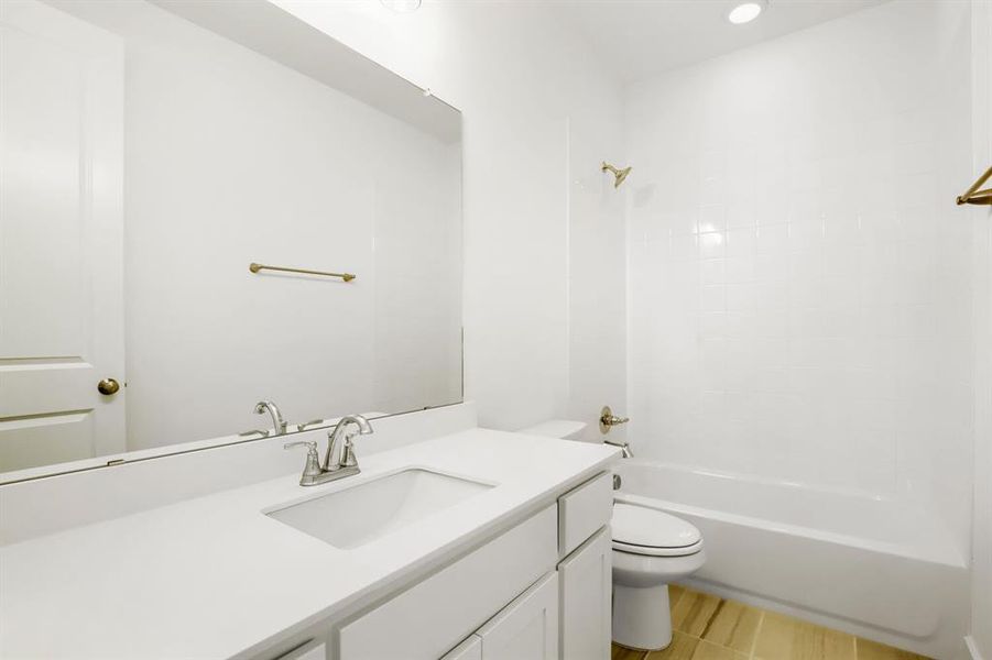 Bathroom vanity featuring a single sink, chrome faucet, and expansive wall-mounted mirror