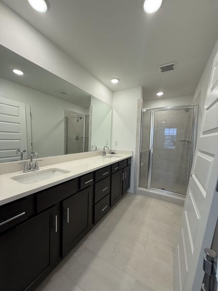 Full bathroom with double vanity, a stall shower, and recessed lighting
