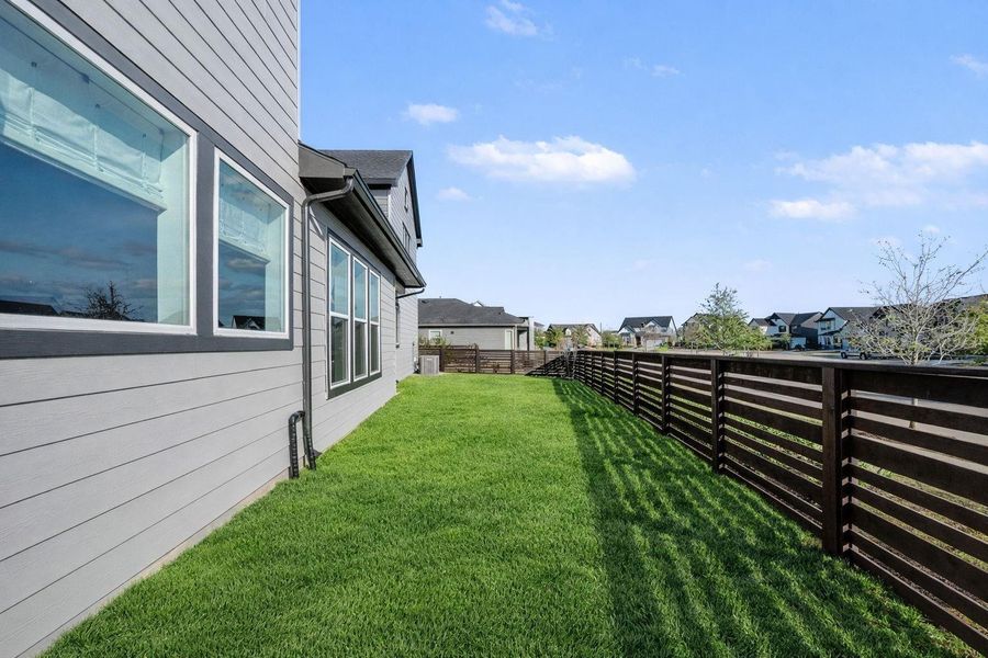 Spacious side yard with modern horizontal fencing offers privacy and room to play, garden, or relax. Clean exterior lines and abundant windows bring in natural light while maintaining a bright, open feel.