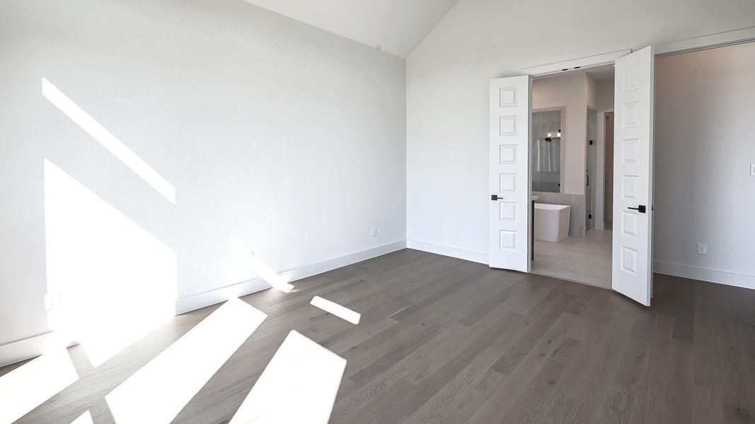 Unfurnished bedroom with lofted ceiling, dark wood finished floors, and connected bathroom Unfurnished bedroom with lofted ceiling, dark wood finished floors, and connected bathroom
