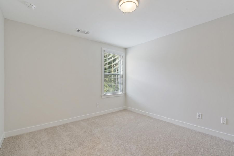 Neutral-toned carpeting, single window with blinds, overhead flush mount lighting, and light-colored walls