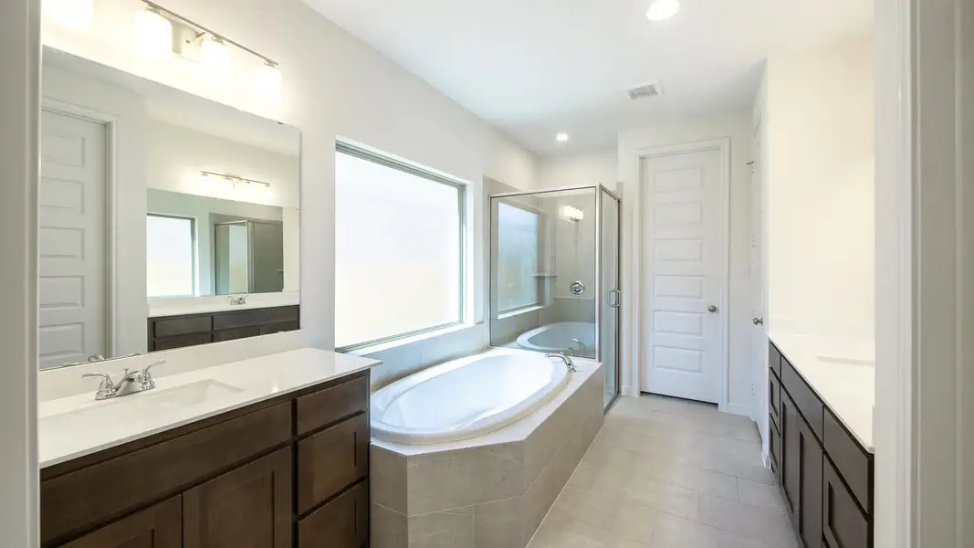 Full bathroom with two vanities, a shower stall, a garden tub, tile patterned floors, and recessed lighting Full bathroom with two vanities, a shower stall, a garden tub, tile patterned floors, and recessed lighting