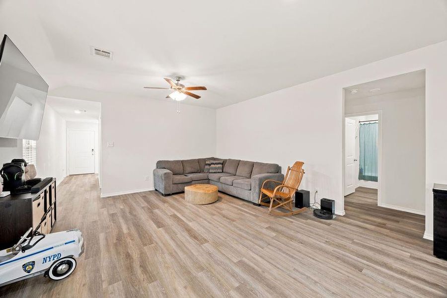 Spacious interior showcasing wood-finish flooring throughout, bright white walls, and an overhead ceiling fan Spacious interior showcasing wood-finish flooring throughout, bright white walls, and an overhead ceiling fan