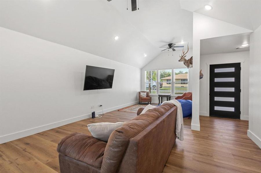 Living area featuring lofted ceiling, wood finished floors, a ceiling fan, and recessed lighting