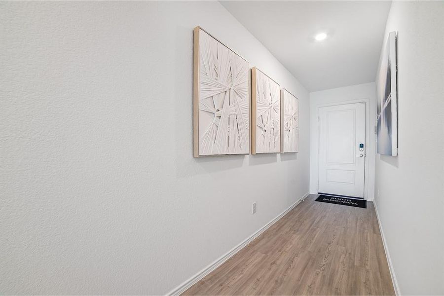 Corridor featuring light wood-style flooring and baseboards Corridor featuring light wood-style flooring and baseboards