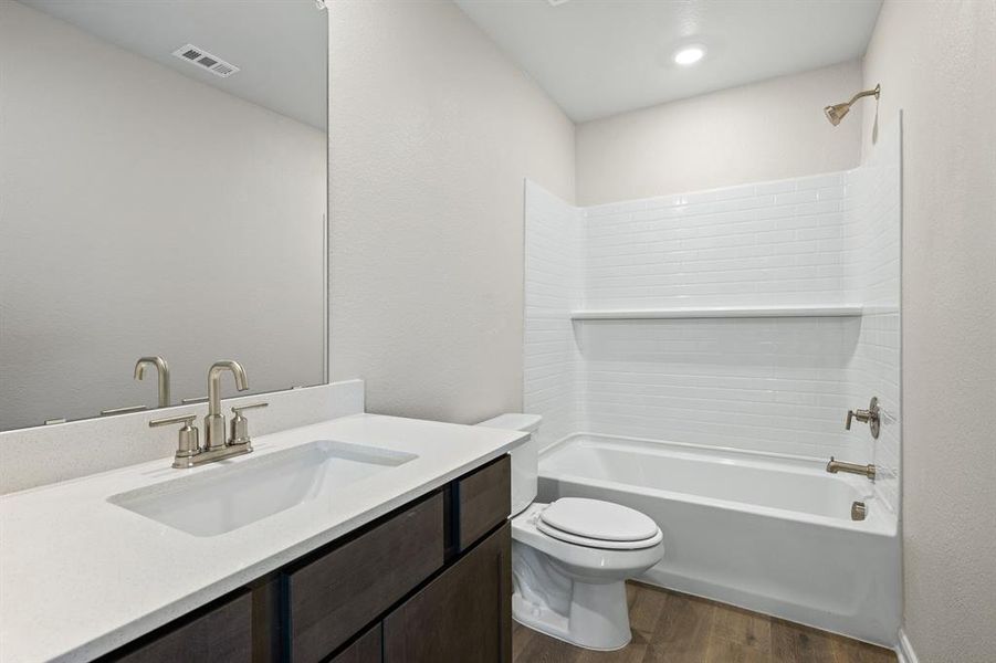 Full bath with dark wood-type flooring, shower / tub combination, vanity, and a textured wall
