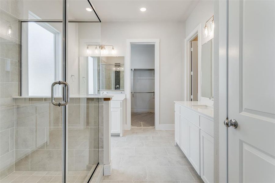 Bathroom with tile patterned floors, a shower with door, and vanity