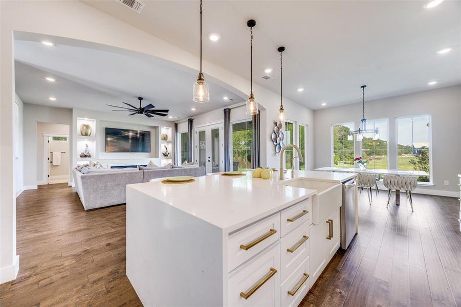 Kitchen featuring white cabinets, hanging light fixtures, light stone counters, open floor plan, and recessed lighting