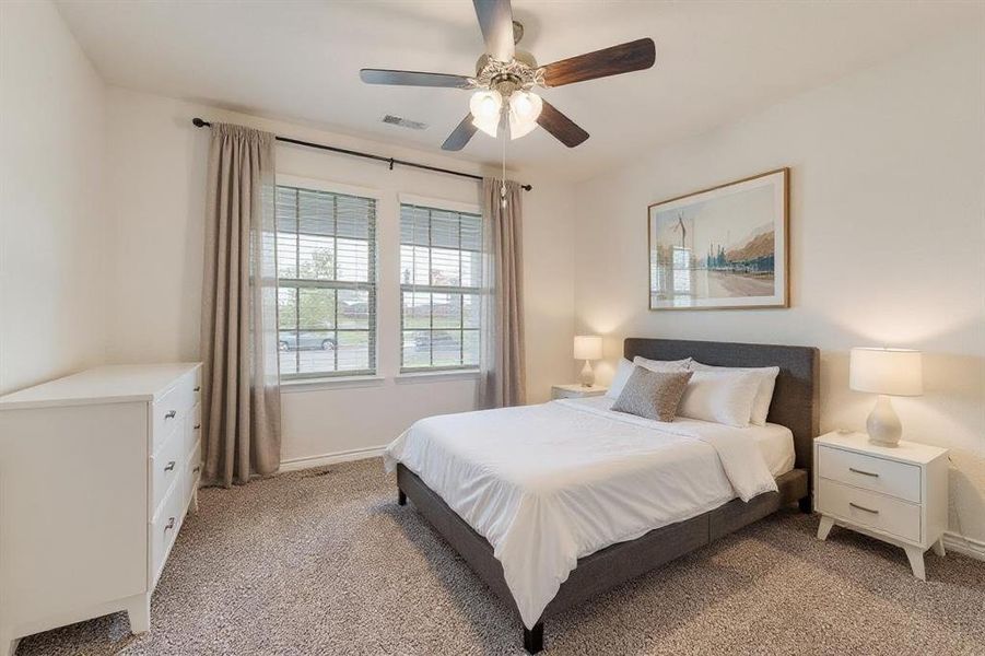 Bedroom with light colored carpet and a ceiling fan