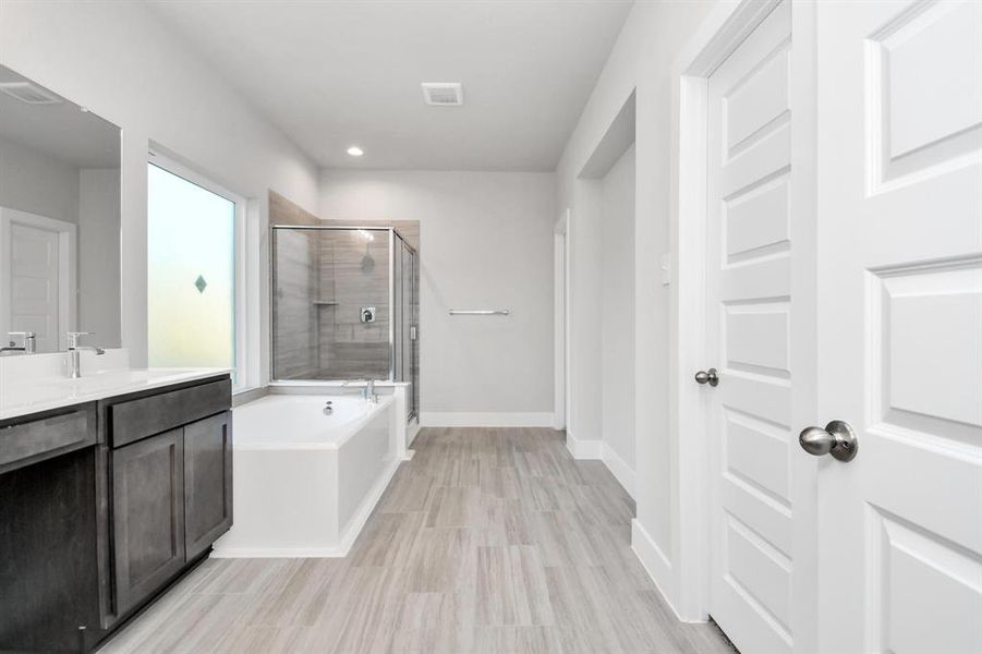 The primary en-suite has a soaking tub to give you that spa experience. The large privacy window allow lots of nature light in the space. Sample photo of completed home. Actual colors and selections will vary.