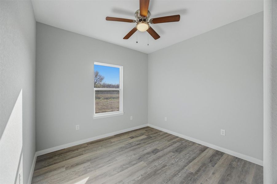 Well-lit room featuring durable wood-like vinyl flooring and a modern ceiling fan.