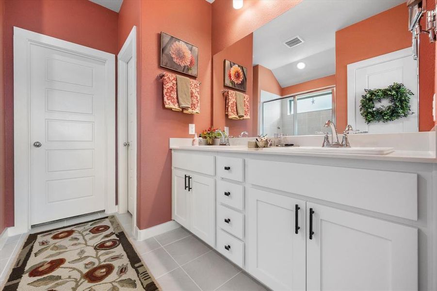 Bathroom featuring double vanity, a stall shower, light tile patterned flooring, and lofted ceiling Bathroom featuring double vanity, a stall shower, light tile patterned flooring, and lofted ceiling