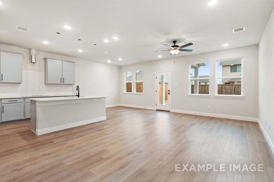 Unfurnished living room featuring ceiling fan, light hardwood / wood-style flooring, and sink