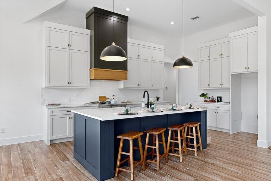 Kitchen with backsplash, light wood finished floors, light countertops, white cabinets, and recessed lighting