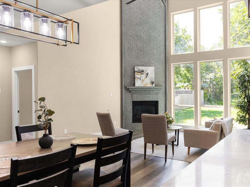 Dining room featuring wood finished floors, a large fireplace, plenty of natural light, and a high ceiling
