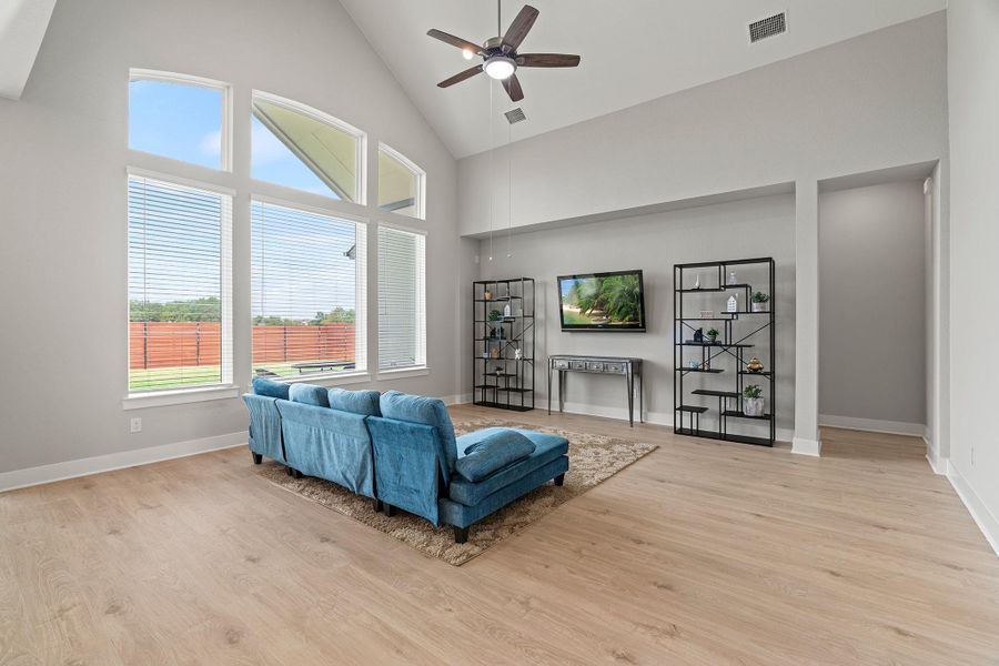 Living area featuring high vaulted ceiling, a ceiling fan, and light wood finished floors Living area featuring high vaulted ceiling, a ceiling fan, and light wood finished floors