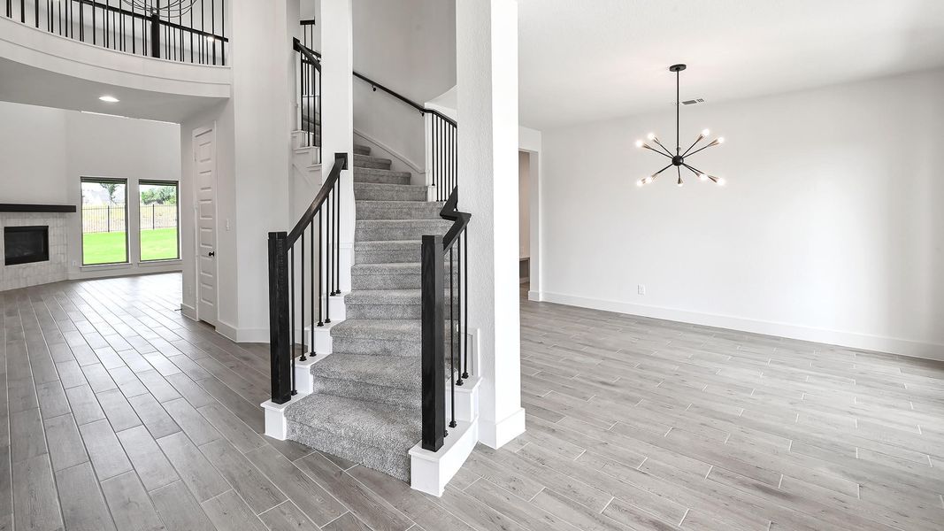 Stairs with wood finished floors, baseboards, a chandelier, a fireplace, and a high ceiling