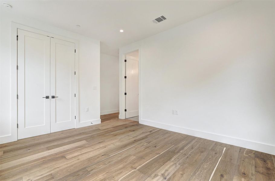 Unfurnished bedroom with light wood-style flooring, a closet, and recessed lighting Unfurnished bedroom with light wood-style flooring, a closet, and recessed lighting