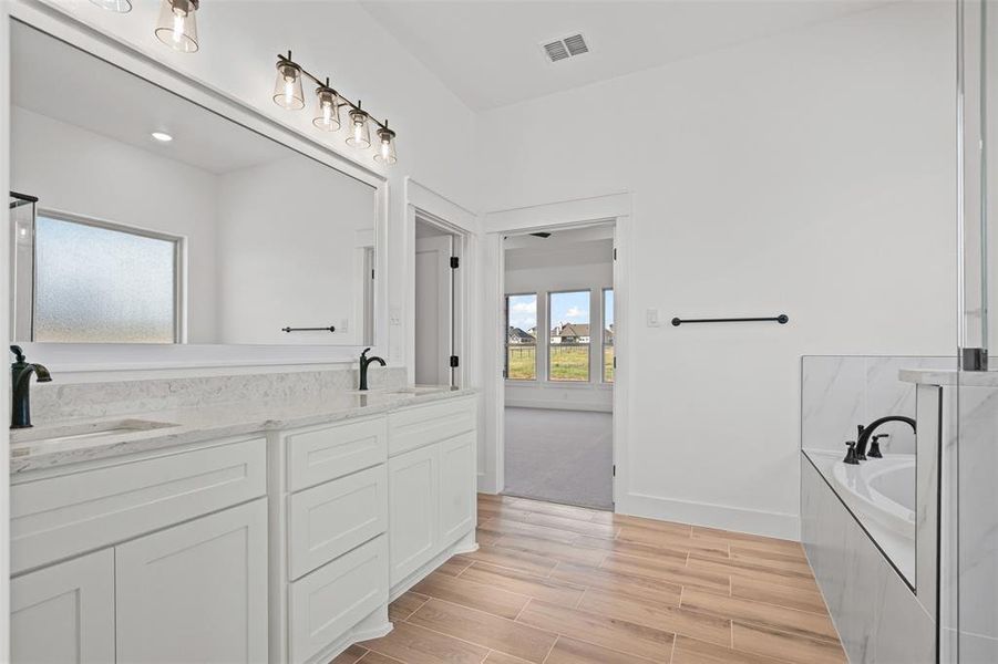Full bathroom with a bath, double vanity, and wood finish floors