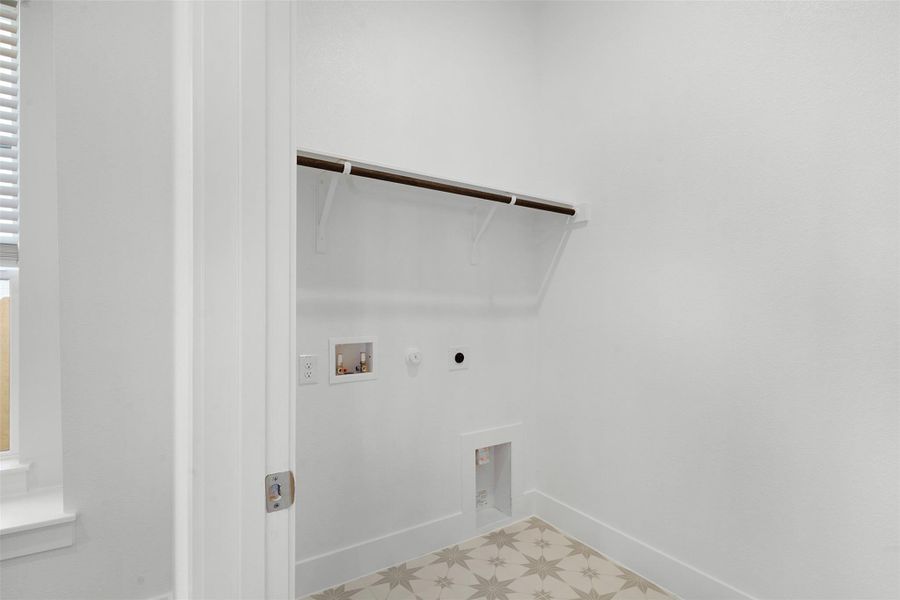 A well-appointed utility room features a convenient hanging rod and an appealing patterned tile floor.