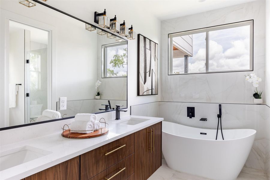 The bathroom features a luxurious soaking tub, dual sinks, and a warm wood vanity, creating a serene, spa-like atmosphere for ultimate relaxation.