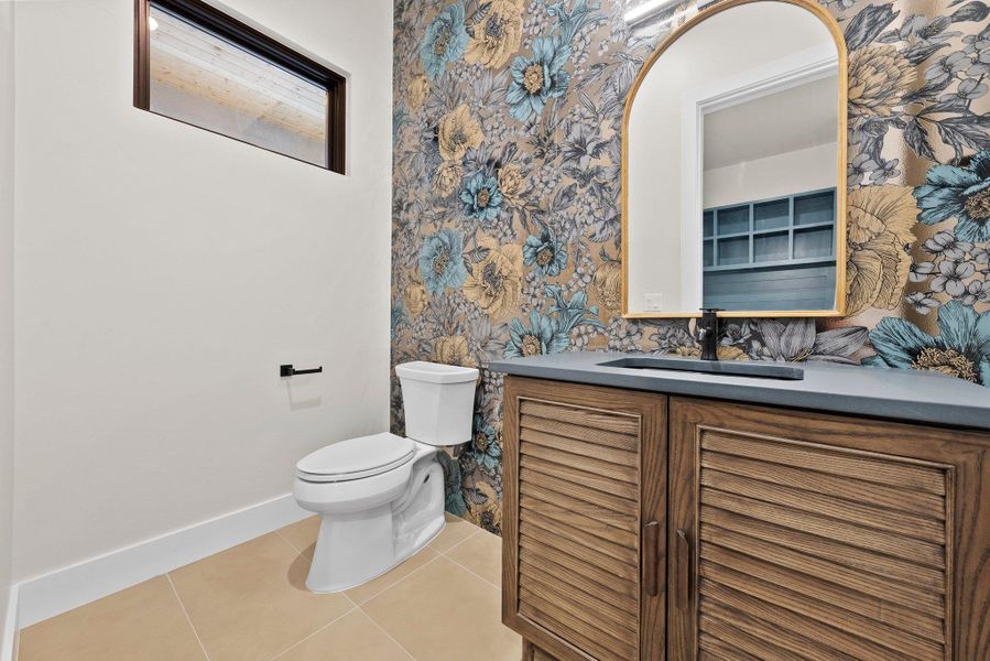 Bold floral wallpaper enlivens this powder room with a sleek vanity and modern fixtures.