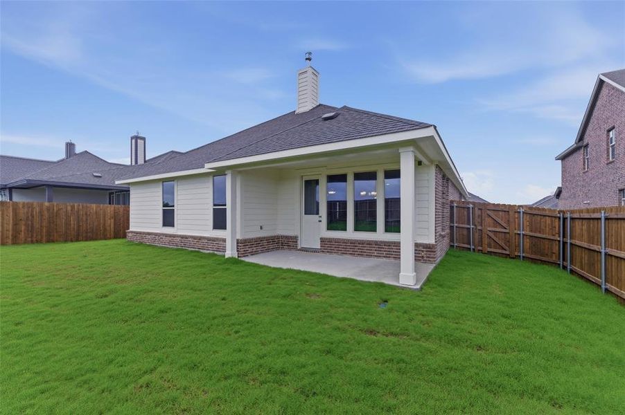 Expansive green lawn surrounds a covered patio featuring a white column and large windows