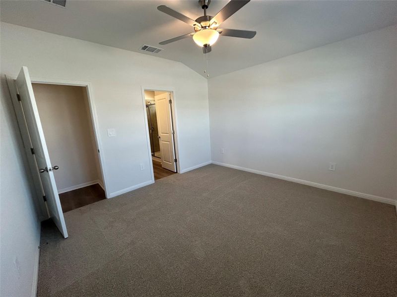 Unfurnished bedroom with lofted ceiling, carpet floors, and ceiling fan Unfurnished bedroom with lofted ceiling, carpet floors, and ceiling fan