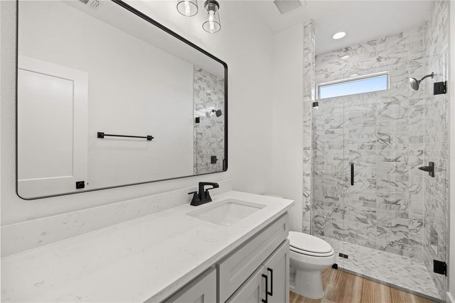 Full bath featuring a stall shower, vanity, light wood-style flooring, and recessed lighting Full bath featuring a stall shower, vanity, light wood-style flooring, and recessed lighting