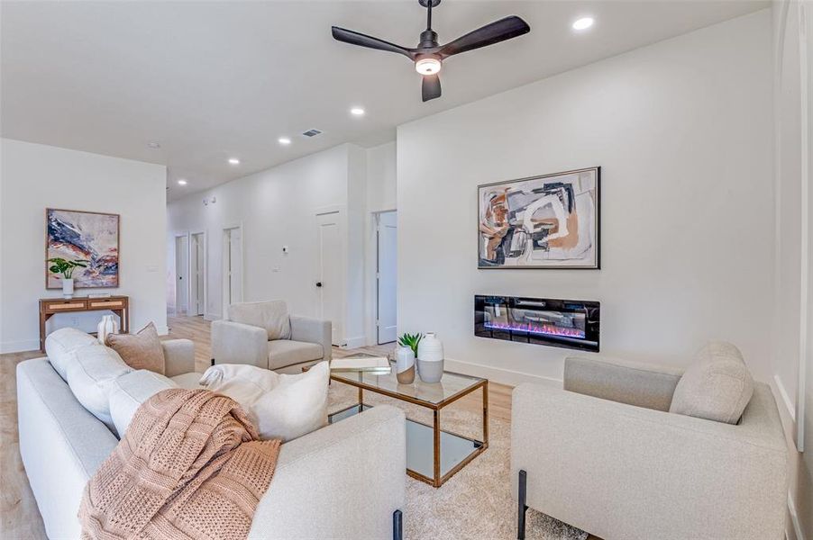 Living area with a glass covered fireplace, recessed lighting, wood finished floors, and ceiling fan Living area with a glass covered fireplace, recessed lighting, wood finished floors, and ceiling fan