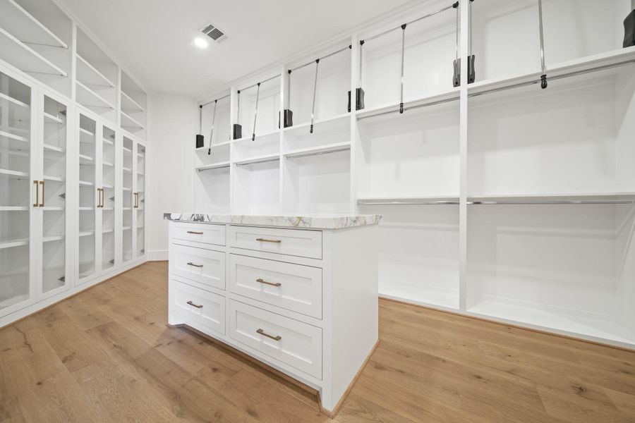 One of TWO oversized closet fitting all your needs. Custom display cabinetry, pull downs for those hard to reach shelves, and a custom drawer island with a quartzite countertop. One of TWO oversized closet fitting all your needs. Custom display cabinetry, pull downs for those hard to reach shelves, and a custom drawer island with a quartzite countertop.