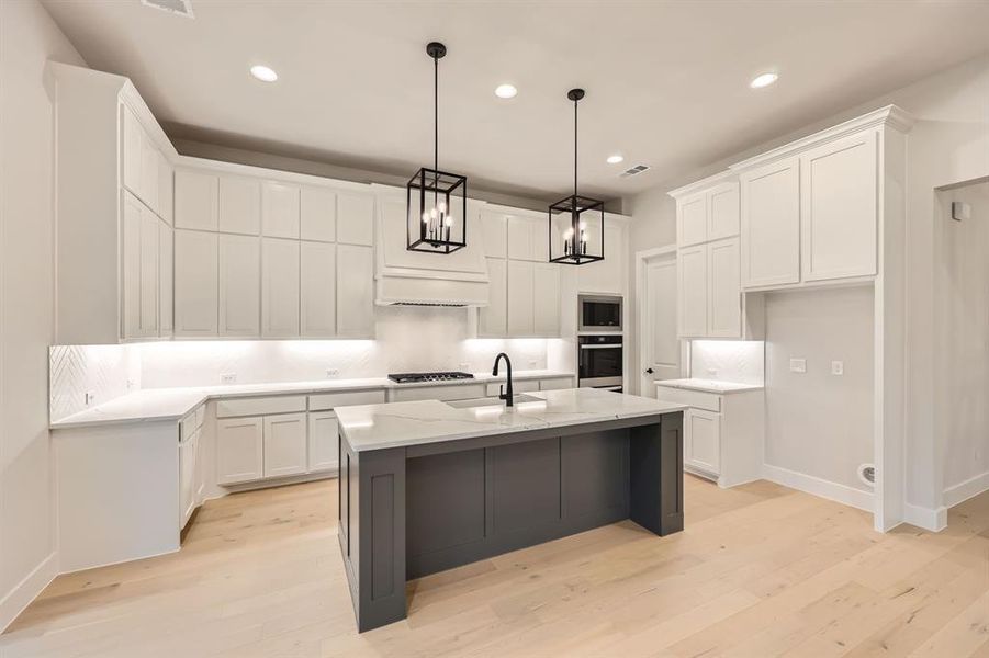 Kitchen featuring a kitchen island with sink, light wood-type flooring, appliances with stainless steel finishes, and white cabinets