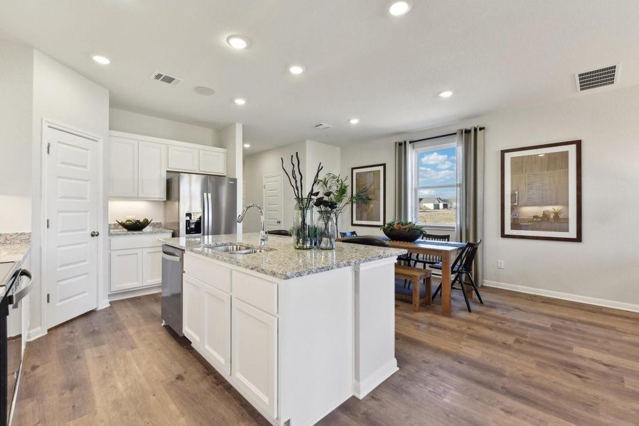 Gleaming stone countertops and warm wood floors define this open kitchen and dining space.