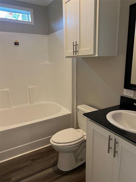 Bathroom featuring dark wood-style floors, vanity, and bathing tub / shower combination