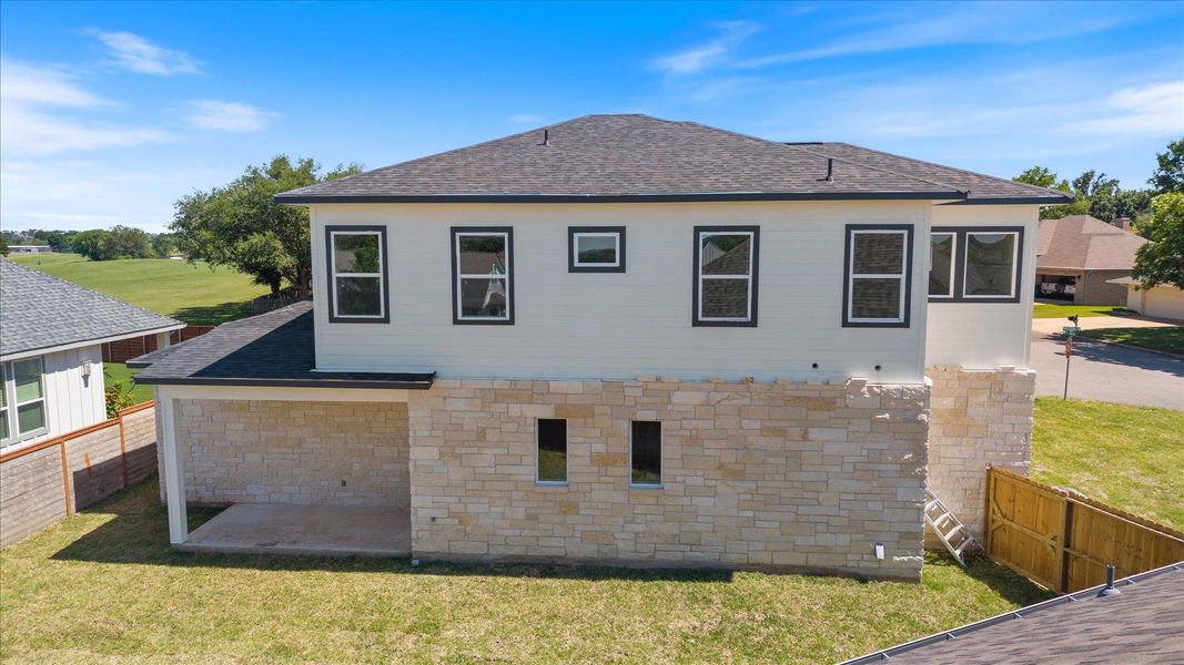 A newly constructed residence features an inviting stone facade and a neatly landscaped yard.
