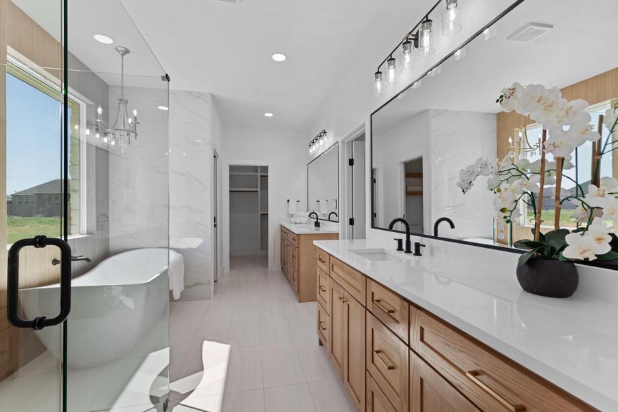 Bathroom with healthy amount of natural light, two vanities, a walk in closet, a freestanding tub, and tile walls Bathroom with healthy amount of natural light, two vanities, a walk in closet, a freestanding tub, and tile walls