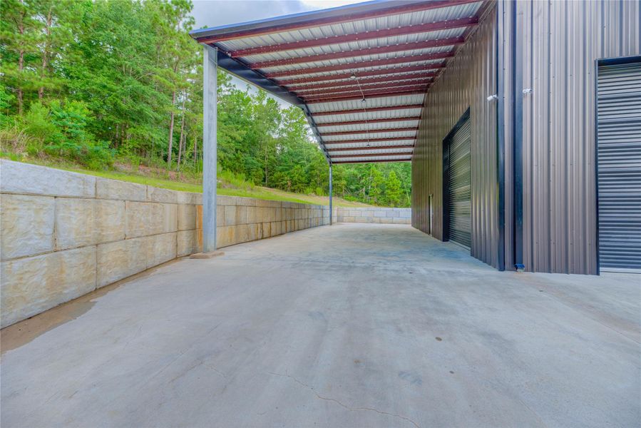 Attached carport area/ side of barndominium building with a retaining wall Attached carport area/ side of barndominium building with a retaining wall