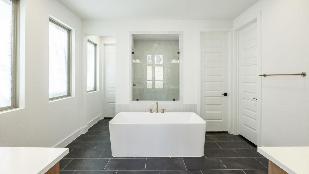 Bathroom featuring vanity, a shower stall, a soaking tub, and dark tile patterned flooring
