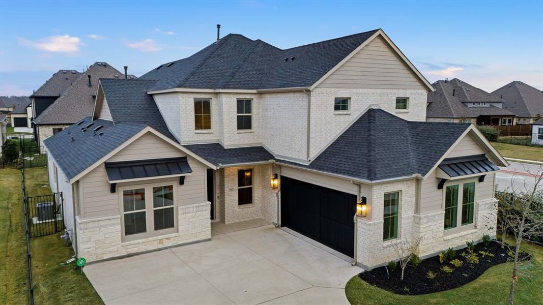 View of front of home with roof with shingles, stone siding, a garage, driveway, and brick siding