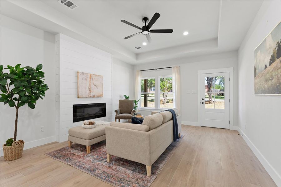 Warm, organic finishes create an inviting space open to the kitchen and dining area. An electric fireplace adds a cozy touch, while large windows overlook the peaceful yard where wildlife is often spotted.