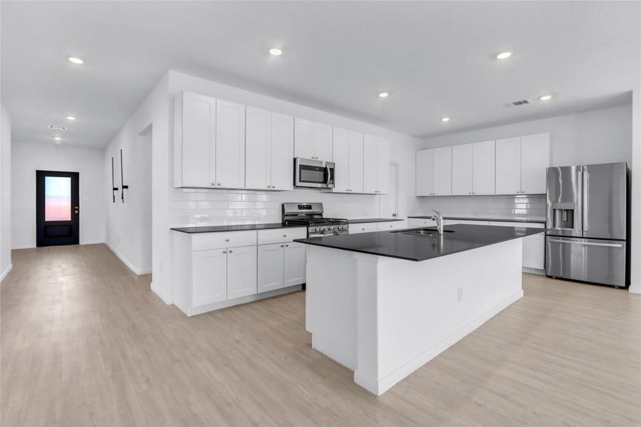 Kitchen featuring white cabinetry, stainless steel appliances, an island with sink, light wood-type flooring, and recessed lighting