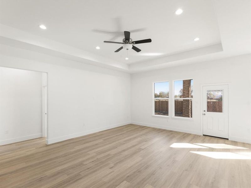 Unfurnished room with light wood finished floors, a tray ceiling, a ceiling fan, and recessed lighting