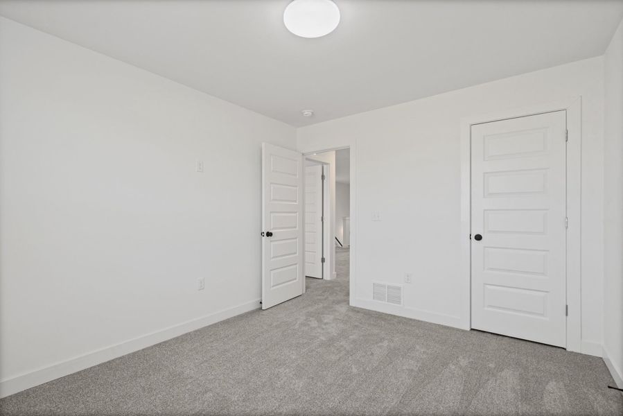 Freshly painted white walls, gray textured carpet, and a modern ceiling light fixture