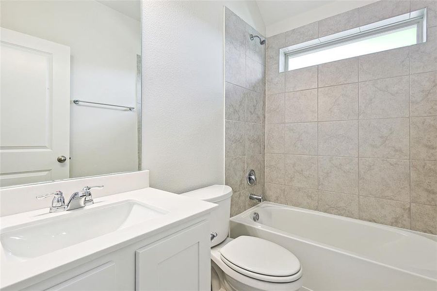 Full bathroom with tiled shower / bath, vanity, and toilet