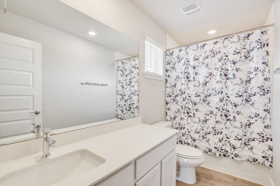 Bathroom featuring recessed lighting, toilet, shower / bath combo, vanity, and wood finished floors