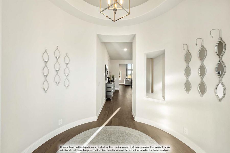 Rounded entryway with tray ceiling, geometric pendant light, hardwood floors, and decorative wall sconces