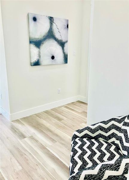 Charming guest bedroom with stylish accents and elegant hardwood flooring.