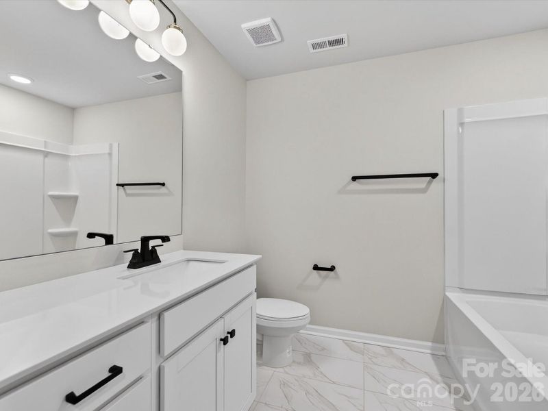 Hall bath features tiled floor, vanity with quartz counters